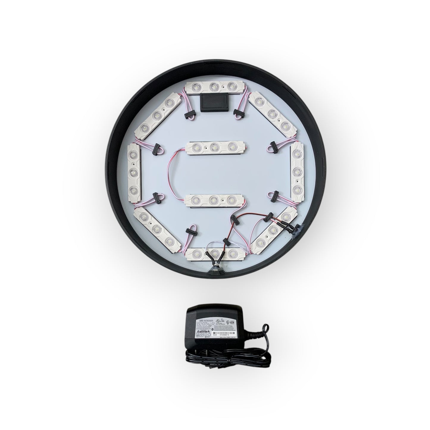 Circular LED light fixture with wiring and a power adapter on a white background