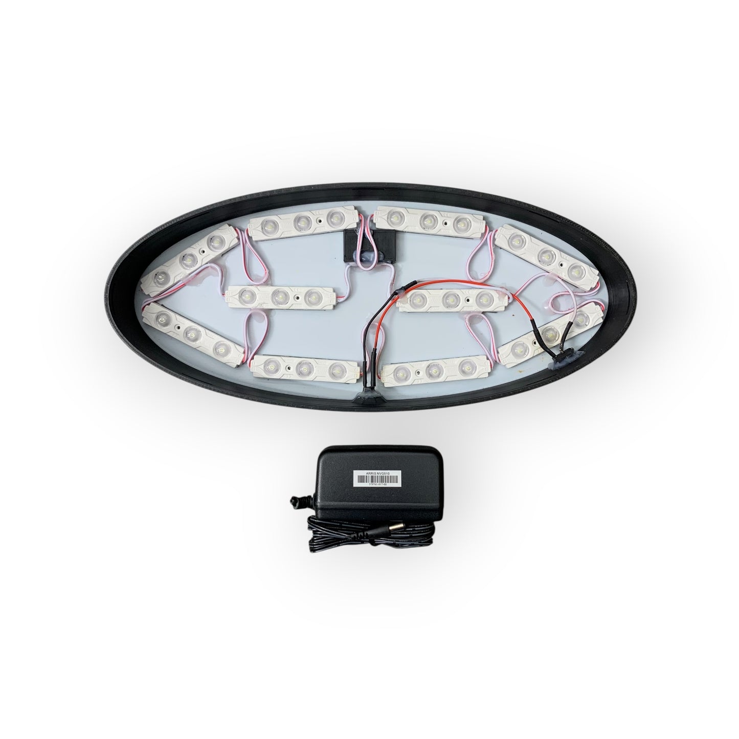 Oval-shaped LED light fixture with wiring and a power adapter on a white background